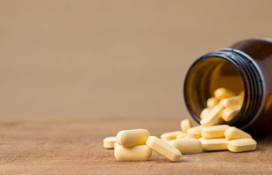 A picture of a bottle of L Carnitine and a bottle of apple cider vinegar next to each other on a wooden table to illustrate the article about taking these two supplements together.