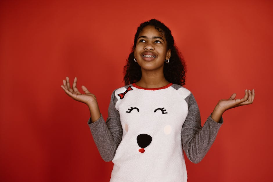 A cartoon image of a person wearing braces holding an apple and looking confused.